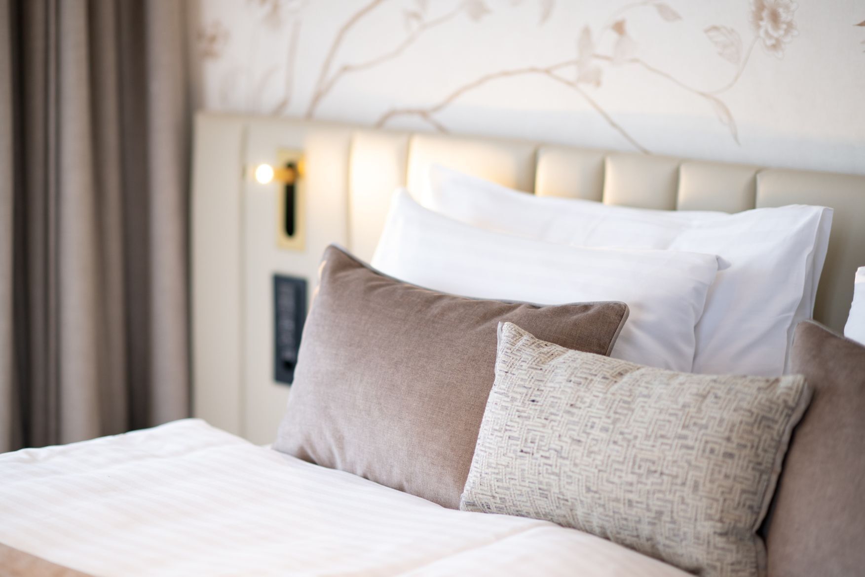 Close-up view of the comfortable bed and pillows with a padded headboard in a bright room at Hotel des Innovations