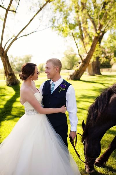 Bride and groom happily embracing near a horse at The Ranch at Ucross, surrounded by the greenery