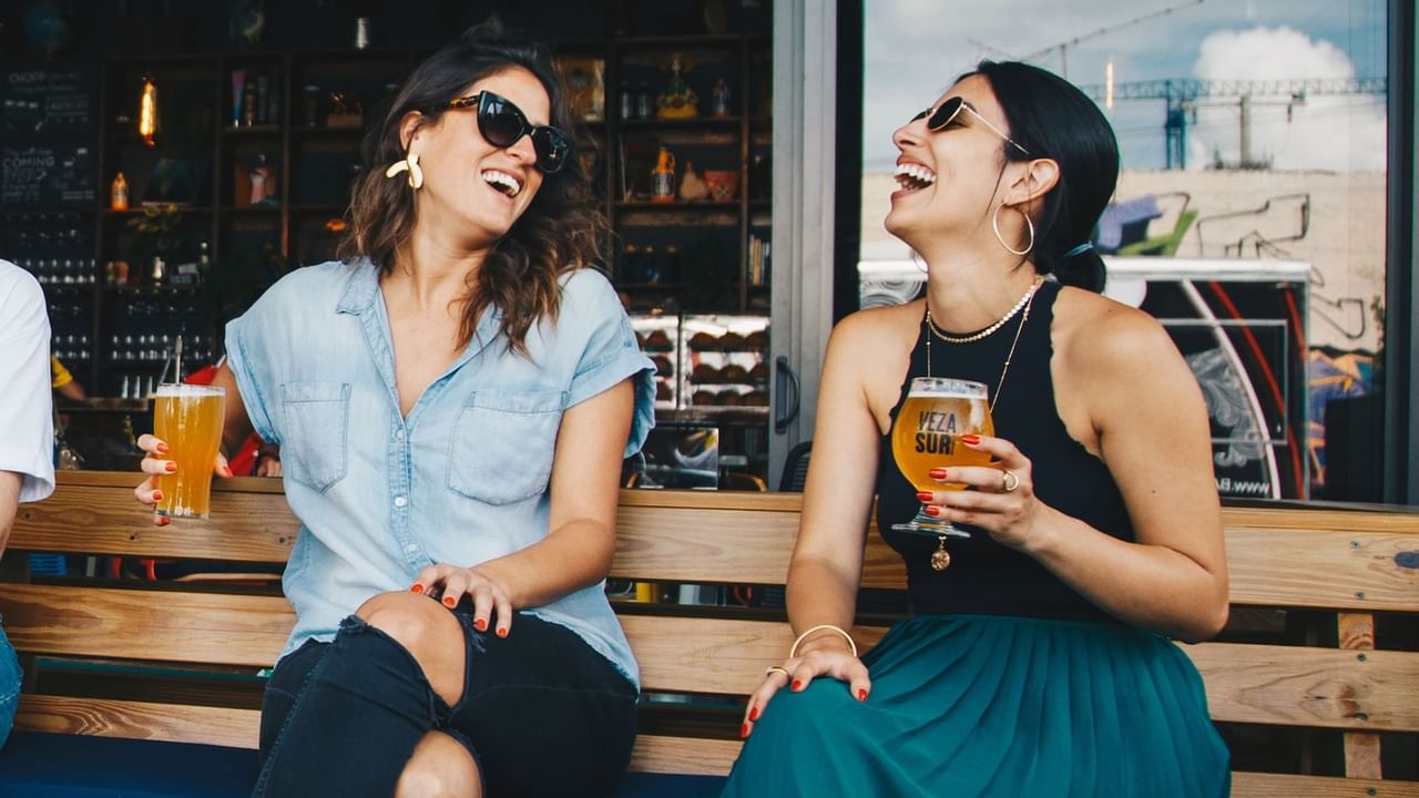 Two girls smiling and laughing drinking beer