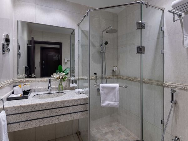 Vanity area with mirror and shower in a bathroom at Warwick Hotel Al Jubail