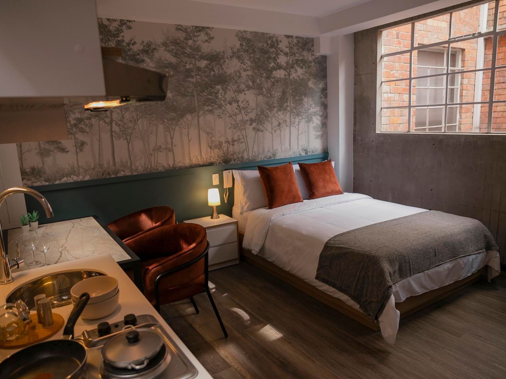 Loft studio with kitchenette, marble counter, warm lighting, and modern bed with a wall art inside 5Q House Quinta Camacho
