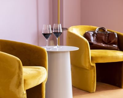 Two wine glasses on a table between yellow armchairs at The Ashbrook Hotel, one of the best hotels in Frankfort Kentucky