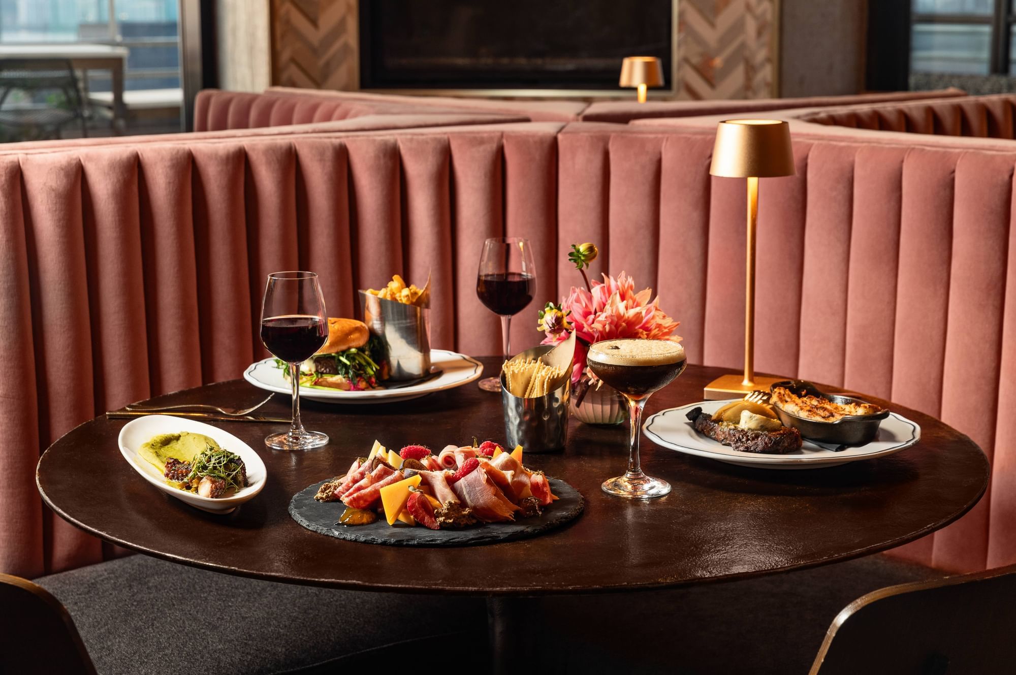 Table set with charcuterie board, steak, burger and glasses of wine