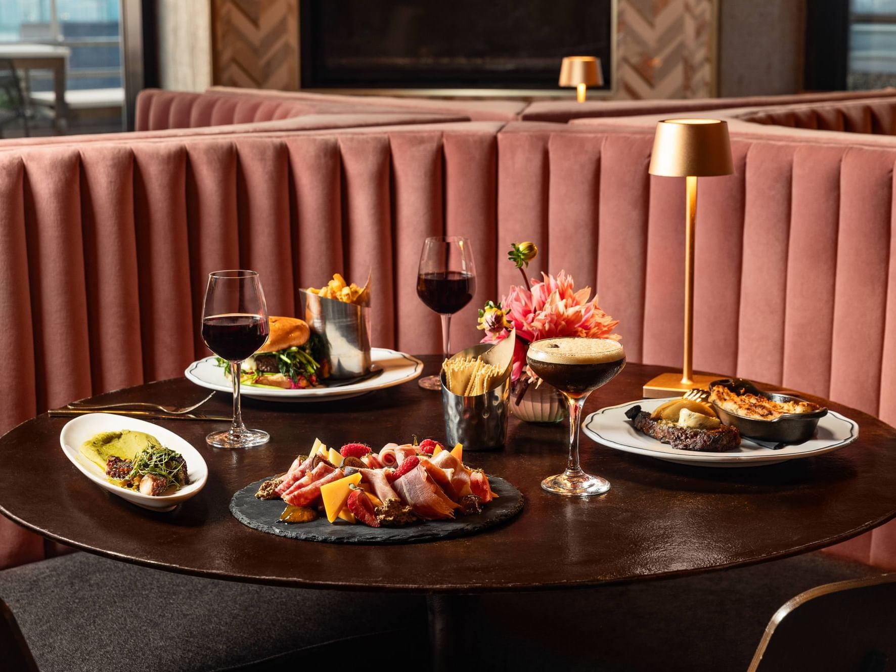 Table set of steak, a burger, charcuterie board and wine