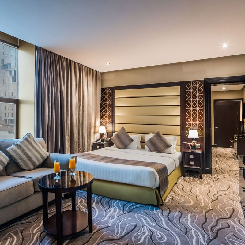 Executive room featuring a queen bed, plush seating, a coffee table and large windows at Warwick Hotels and Resorts