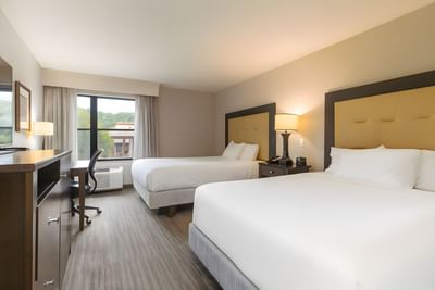 Double Queen Room with two queen beds, dark wood furniture, and a window work desk with a chair at Branson Hillside Hotel