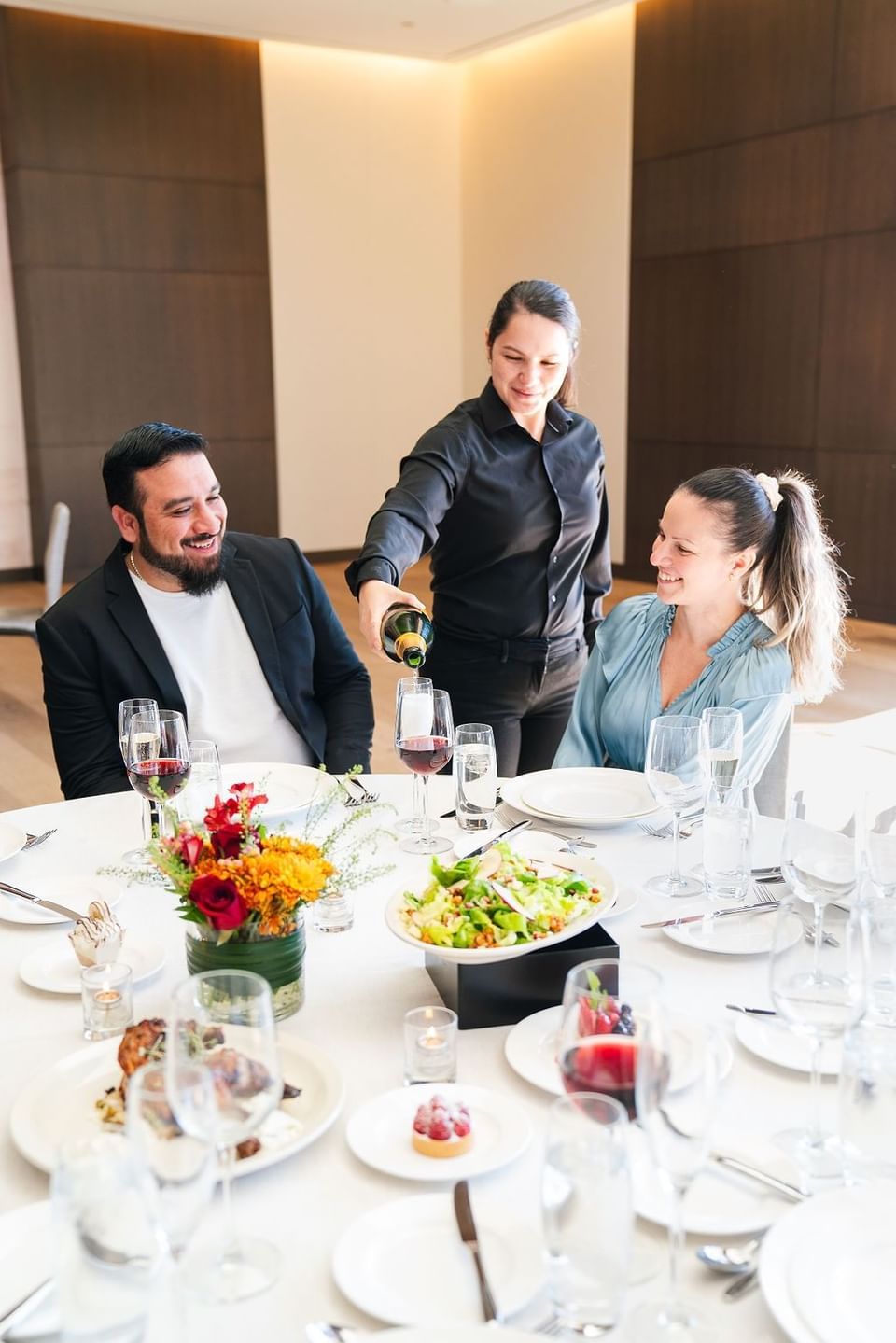 Waiter pouring wine for guests at a finely set dining table in The Study at the University of Chicago