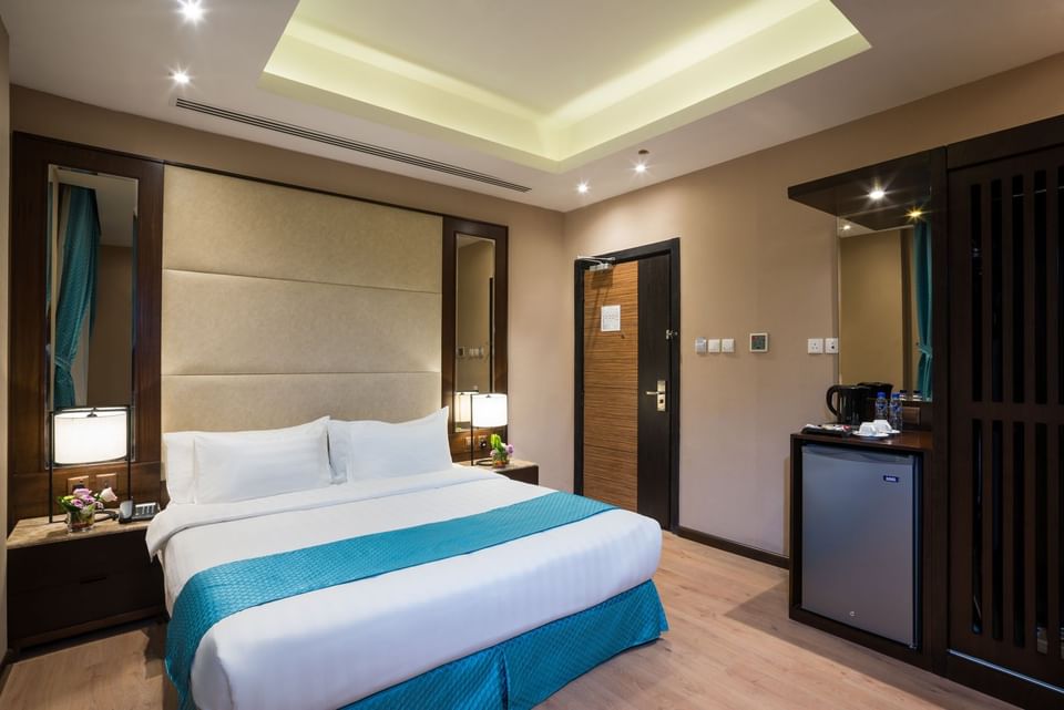 Bed between the side tables and the kitchen cabinet near the door in Standard room at Naviti By Warwick Dammam