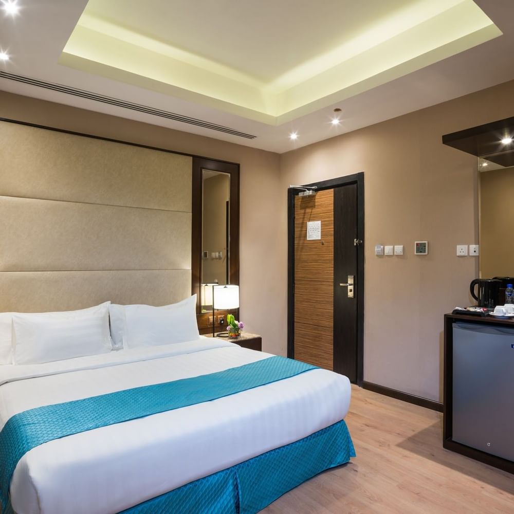 Bed between the side tables and the kitchen cabinet near the door in Standard room at Naviti By Warwick Dammam