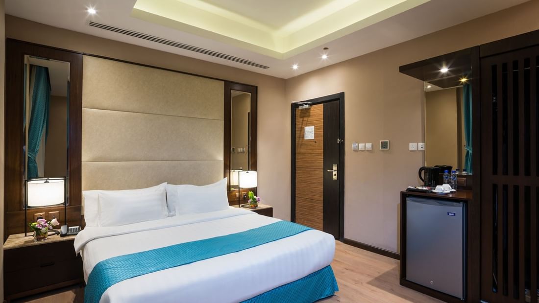 Bed between the side tables and the kitchen cabinet near the door in Standard room at Naviti By Warwick Dammam
