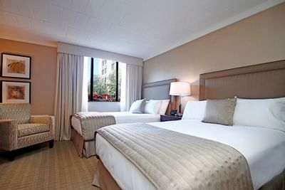Twin double beds with a couch in a room at Ethan Allen Hotel