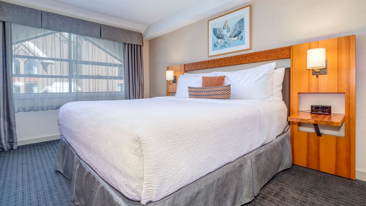 A King bed with white bedding, pillows, and a picture frame on the wall above.