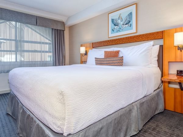 A King bed with white bedding, pillows, and a picture frame on the wall above.