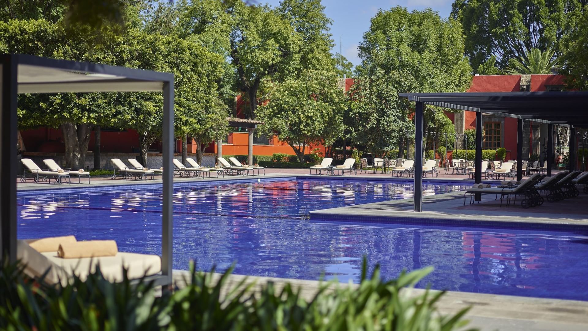Outdoor pool with loungers on deck areas at La Colección