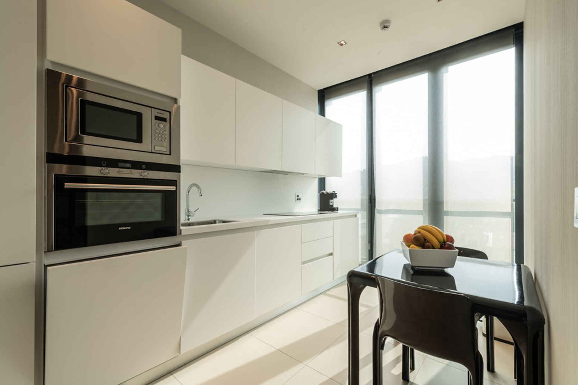 Suite con cucina moderna con tavolo e cesto di frutta a DUPARC Contemporary Suites