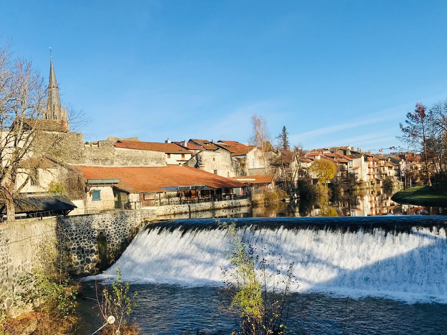 Buildings by a river in Aurillac near The Originals Hotels