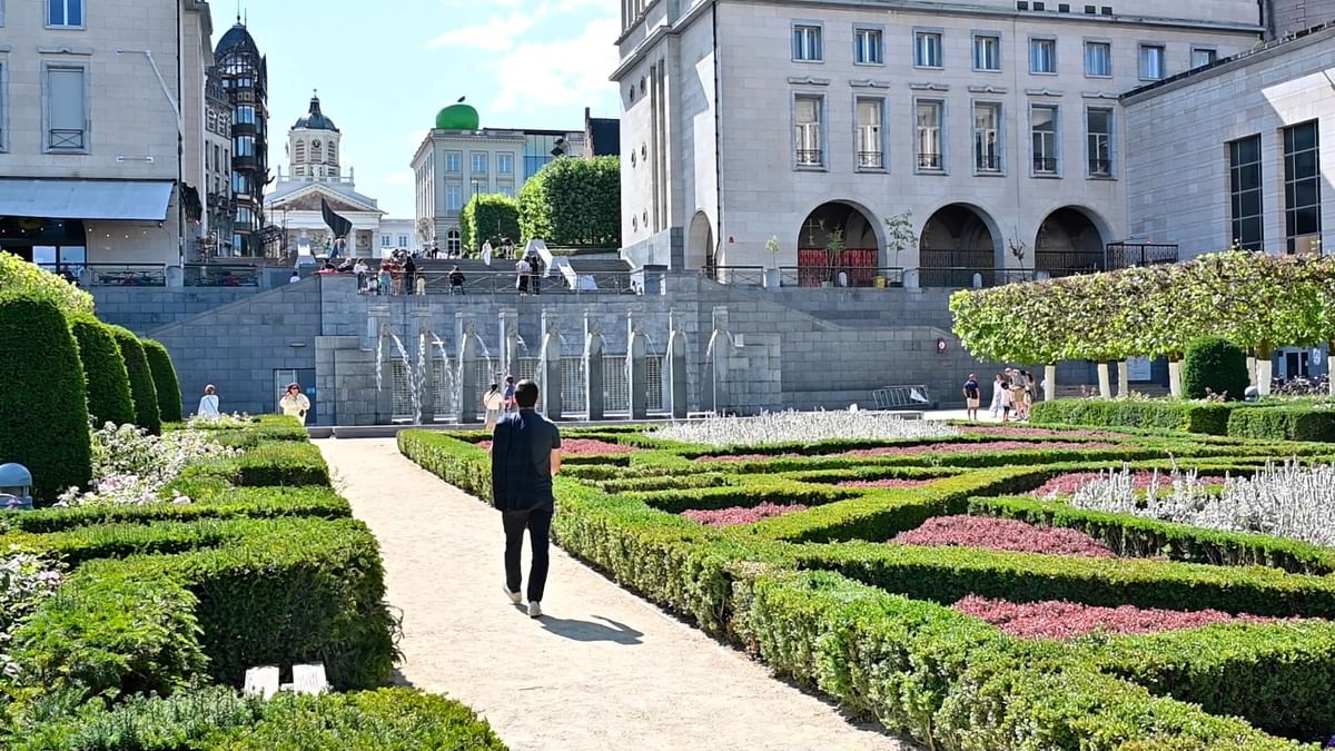 Man walking through the scenic gardens of the Mont des Arts toward the wall fountains at Hotel Barsey by Warwick