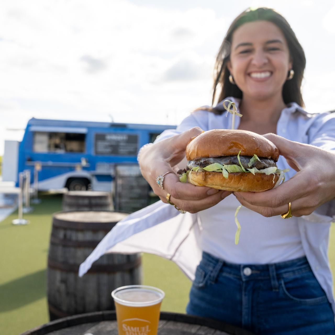 Lady holding a burger by the food truck in Beer Garden at The Artisan Hotel at Tuscan Village