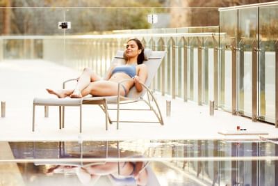 Lady on a pool bed by the pool at Knightsbridge Canberra