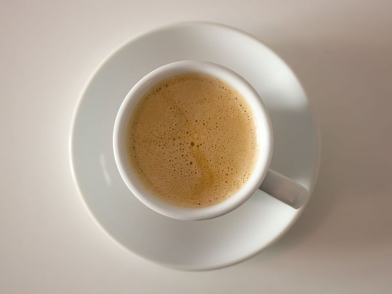 A cup of coffee on a saucer served in the dining area at One Hotels