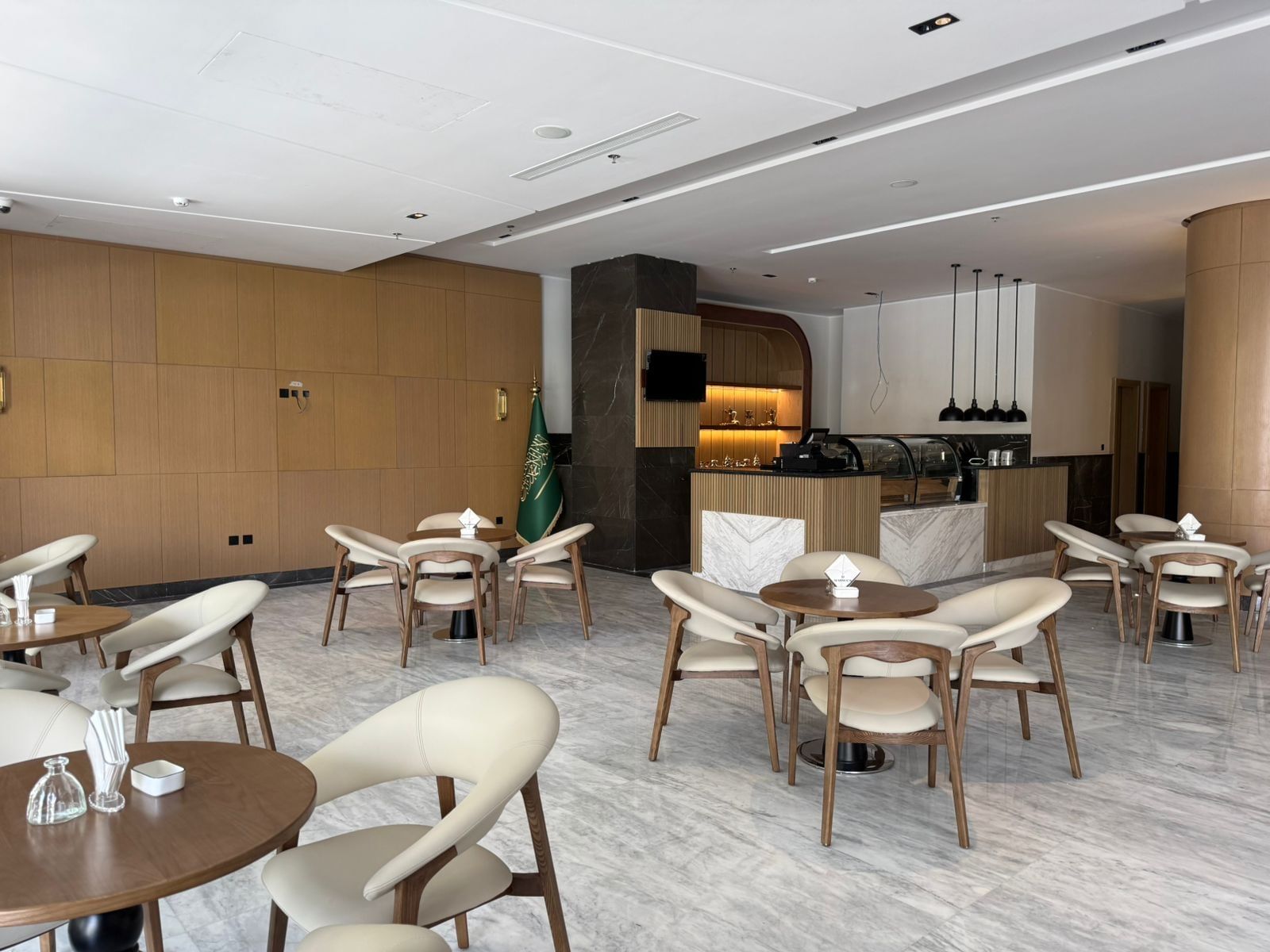 Coffee Lounge with round tables by curved cream chairs under a white ceiling at Warwick Jeddah Hotel & Spa