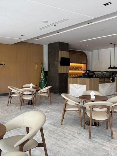 Coffee Lounge with round tables by curved cream chairs under a white ceiling at Warwick Jeddah Hotel & Spa