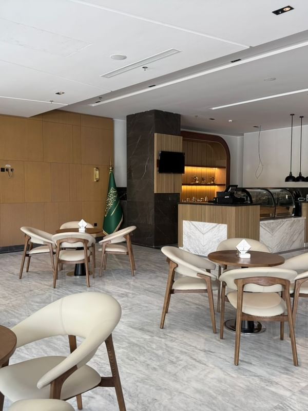 Coffee Lounge with round tables by curved cream chairs under a white ceiling at Warwick Jeddah Hotel & Spa