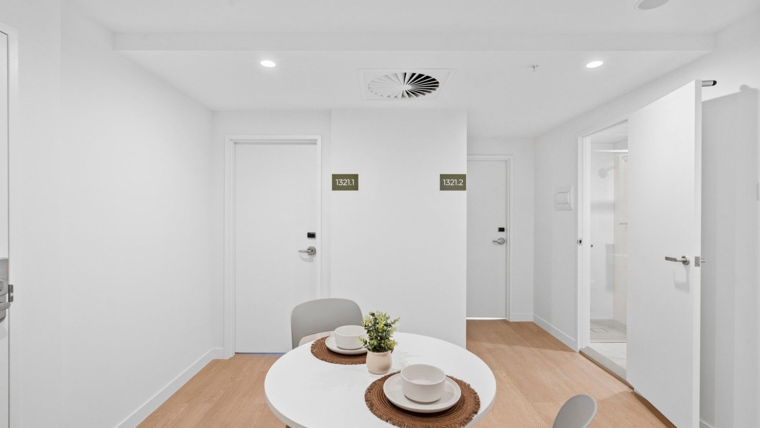 White room with round table and two chairs at UniLodge Brisbane City.