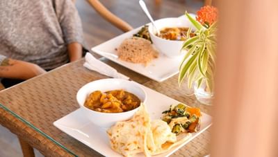 Chicken curry and flatbread with a side salad on a table plate setting in Hott Pott Restaurant at Worthing Court Apartment