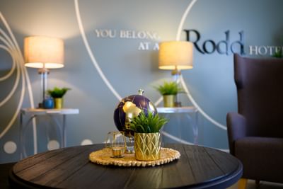 Golden globe ornament and a small green plant in a gold pot on a dark wooden lobby coffee table at Rodd Moncton
