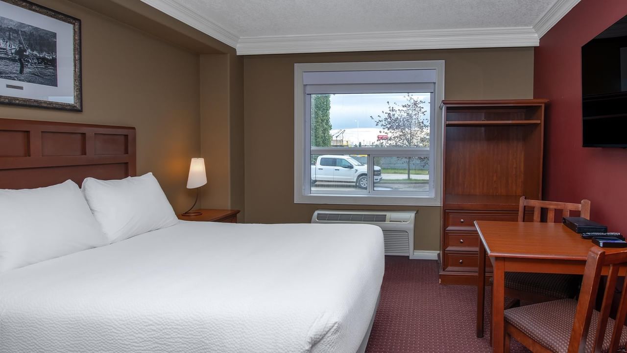 Guest room with king bed, wooden furniture, work desk, and window view at Coast Edson Hotel