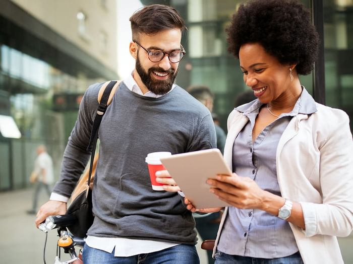 Man and woman smiling and looking at a tablet.