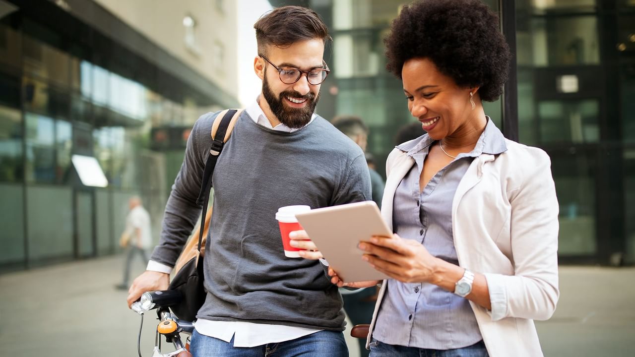 Man and woman smiling and looking at a tablet.