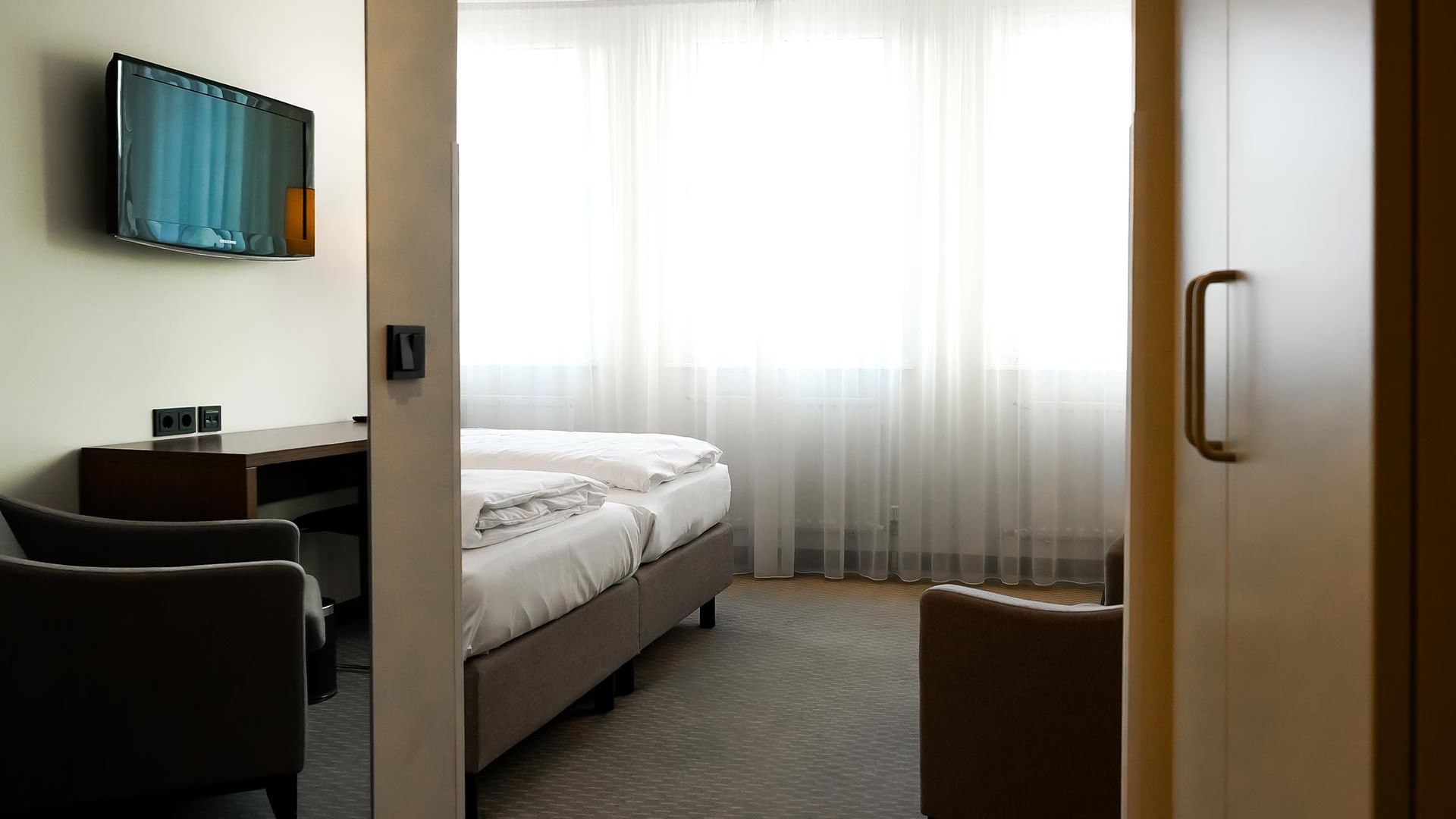 Gemütliches Standard Doppelzimmer mit Bett, Fernseher und Sesseln im Sylter Hof Berlin.