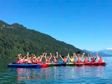 People kayaking on a serene lake surrounded by lush green trees at Harrison Lake Hotel