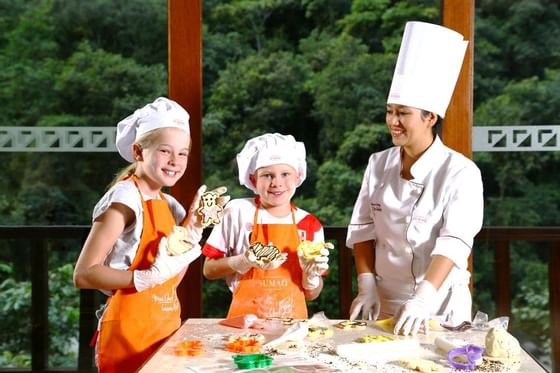 A chef and two kids in aprons making cookies at Hotel Sumaq