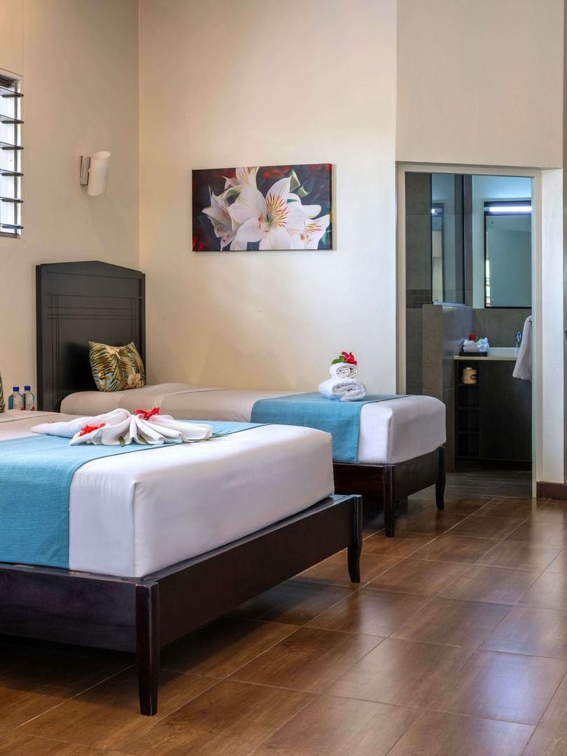 Family Villa interior with two beds, dining area, and bathroom at Tokatoka Resort - Fiji International Airport, Nadi