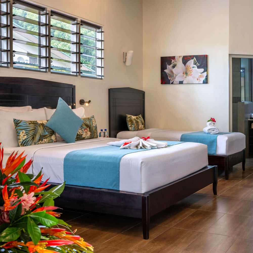 Family Villa interior with two beds, dining area, and bathroom at Tokatoka Resort - Fiji International Airport, Nadi.