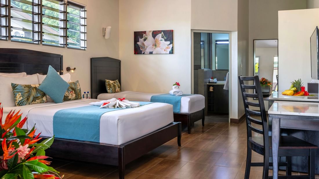 Family Villa interior with two beds, dining area, and bathroom at Tokatoka Resort - Fiji International Airport, Nadi