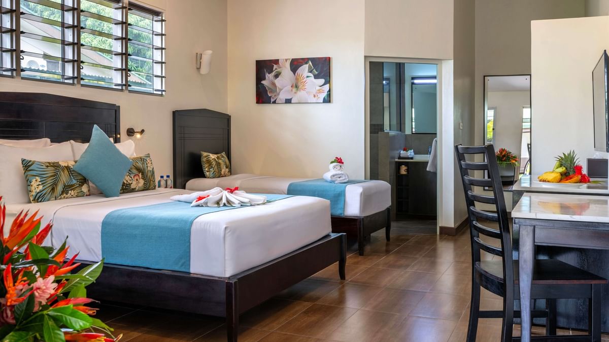 Family Villa interior with two beds, dining area, and bathroom at Tokatoka Resort - Fiji International Airport, Nadi.