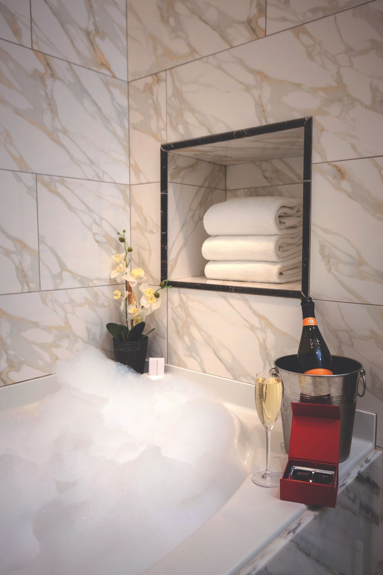 Lorem ipsum Bubble bath with a cup of wine and bottle of wine inside an ice bucket