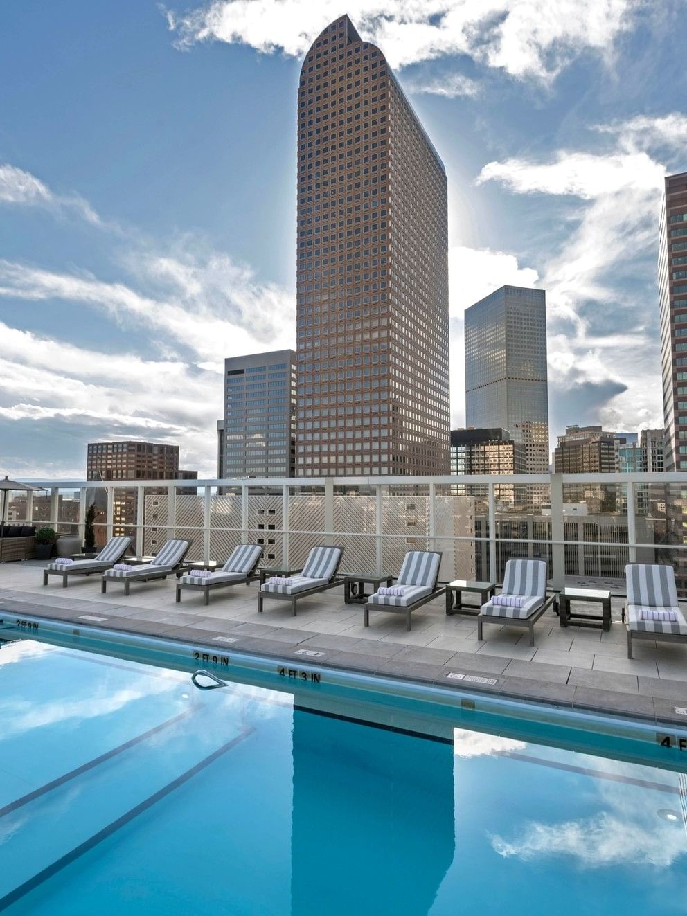 Outdoor pool with lounge chairs and city skyline view at Warwick Denver