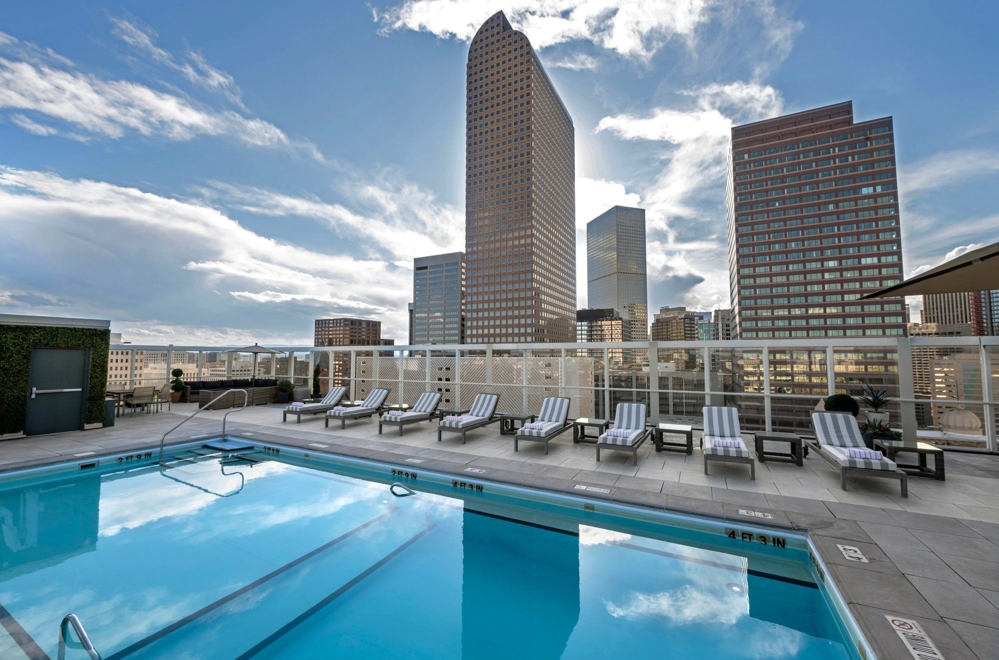 A rooftop pool with lounge chairs and a city skyline view.