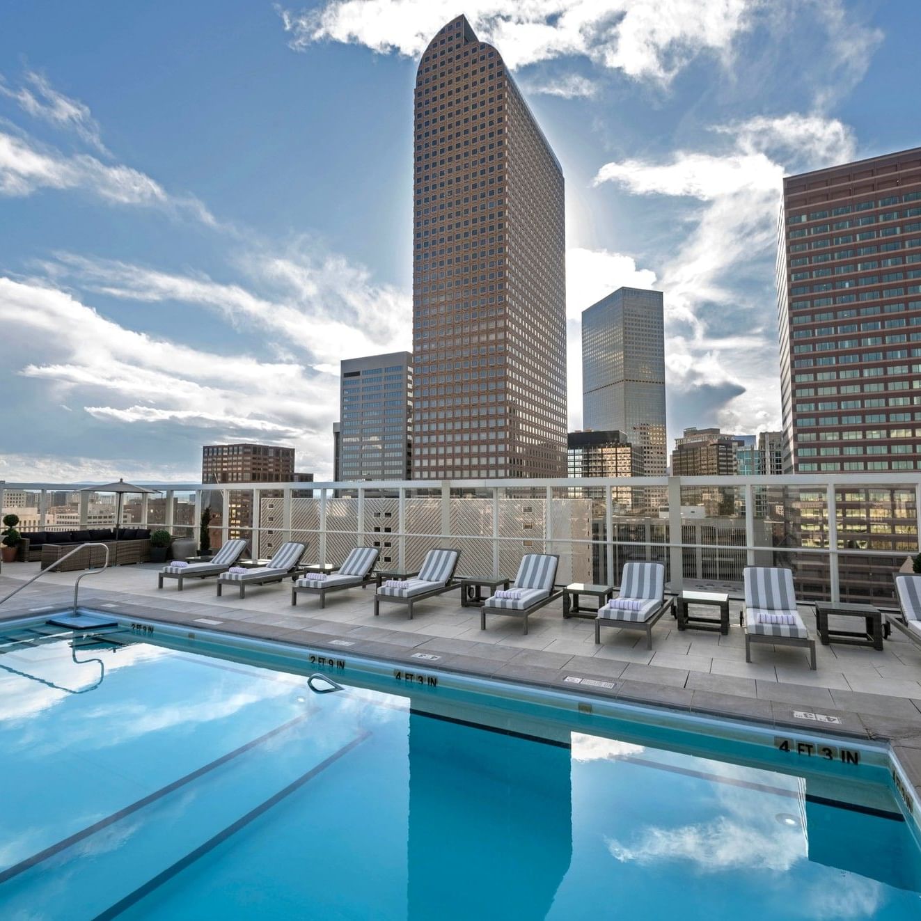 Piscine extérieure avec chaises longues et vue sur les toits de la ville au Warwick Denver.