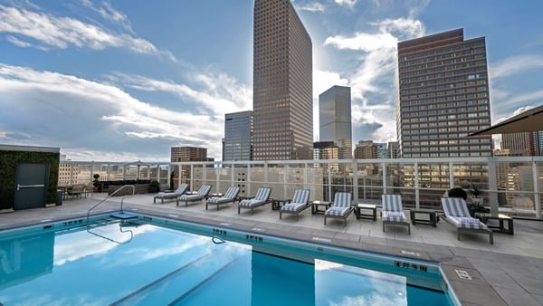Outdoor pool with lounge chairs and city skyline view at Warwick Denver