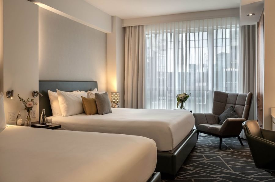 Loft Suite with 2 King Beds and a lounge chair near the window at Warwick Le Crystal Montreal