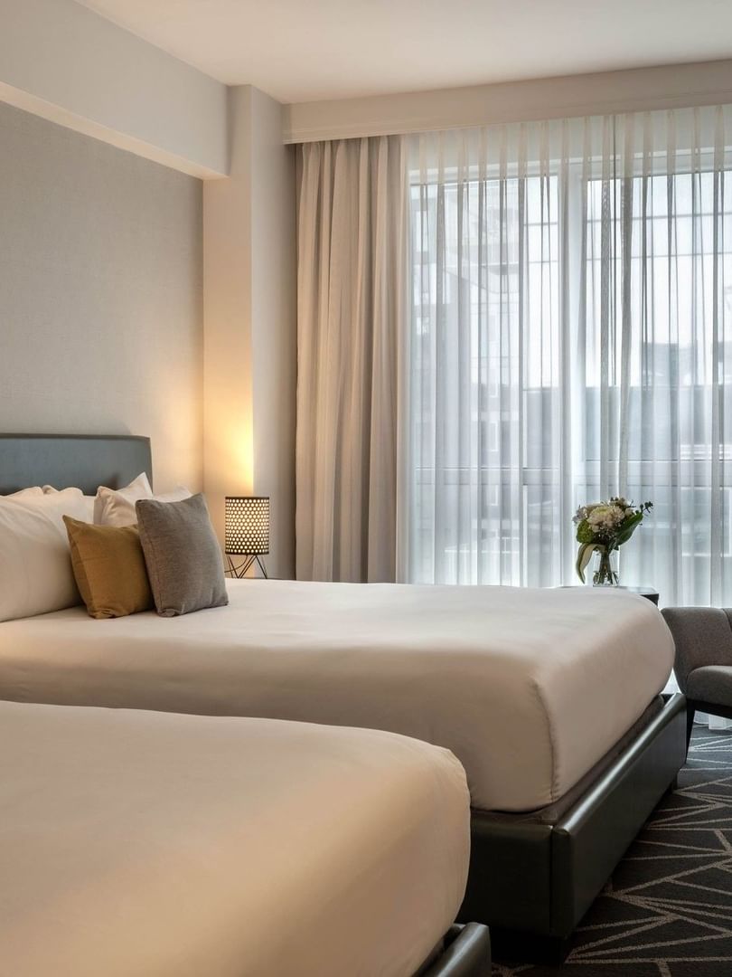 Beds with a side table and couch near the window in Loft Suite 2 King Beds at Warwick Le Crystal Montreal