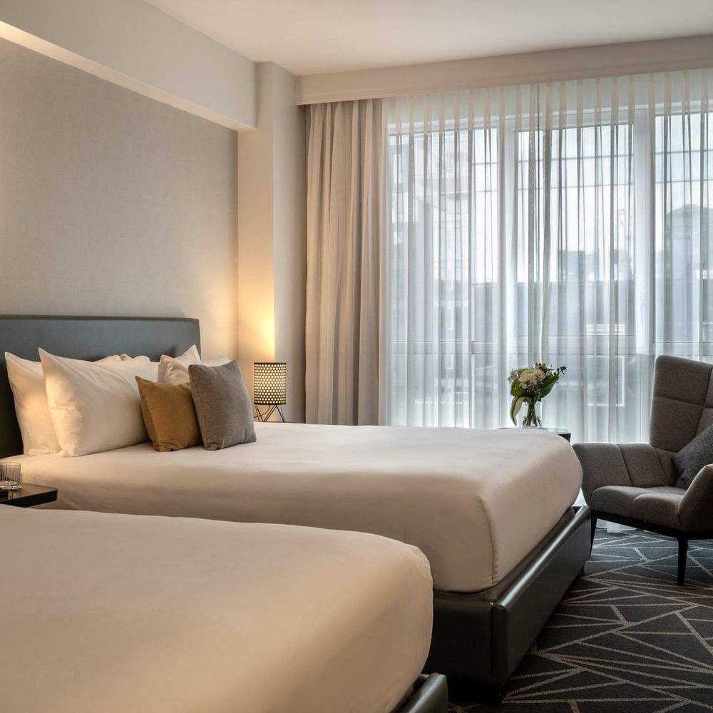 Beds with a side table and couch near the window in Loft Suite 2 King Beds at Warwick Le Crystal Montreal