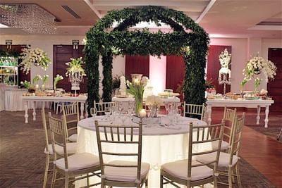 A wedding reception table at Hotel Mykonos with a leafy green archway, elegant white flowers, and table settings