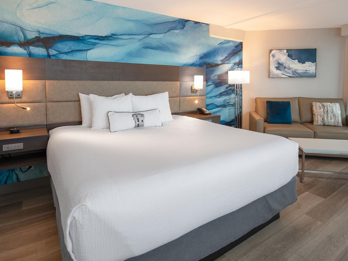 King bed with white linens and sofa in Coast Premium King Suite at Coast Bastion Hotel in Nanaimo.